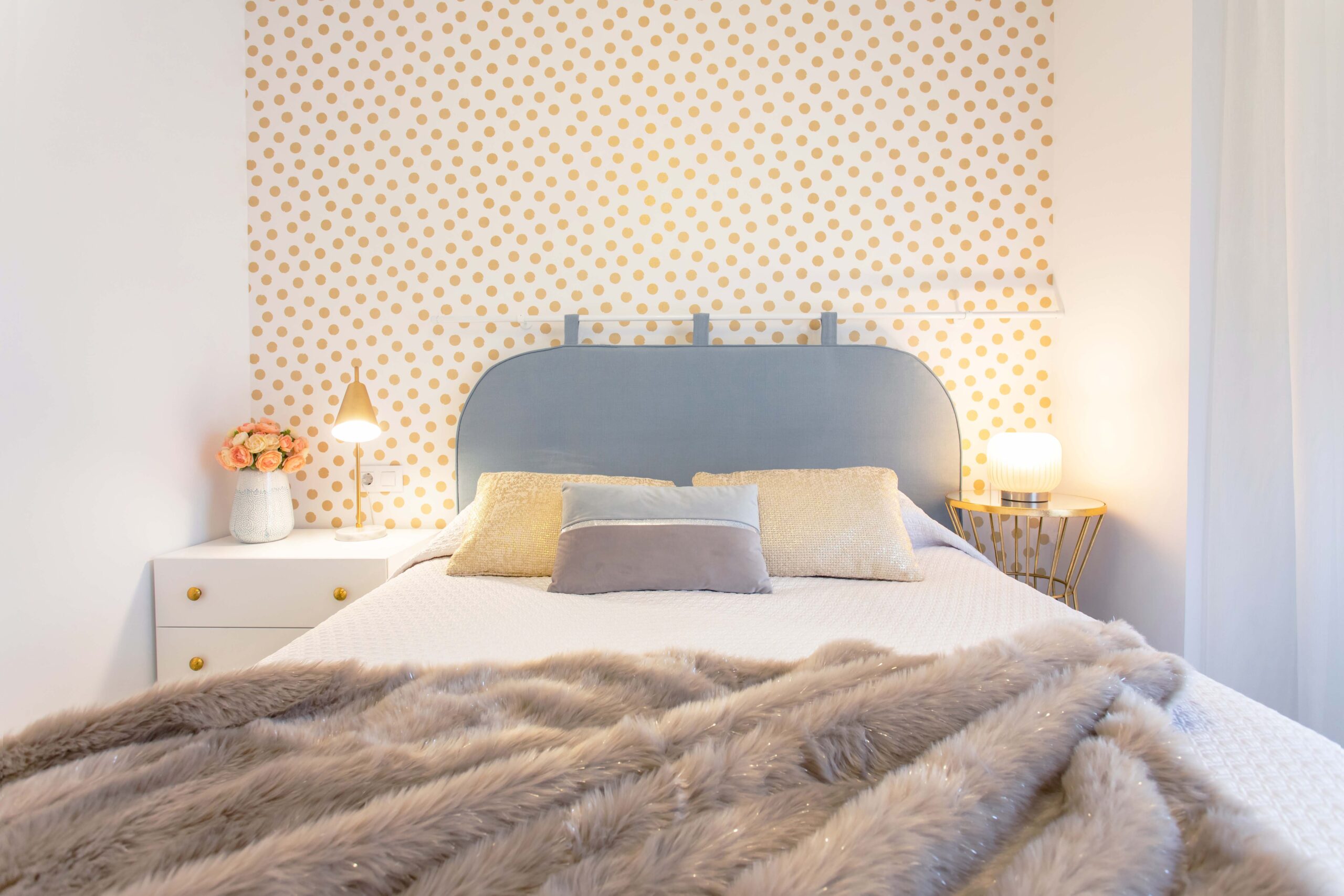 Dormitorio principal con papel decorativo de lunares dorado dando protagonismo al cabezal estilo hotel